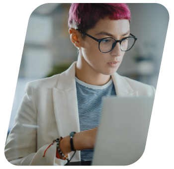 Focused woman with short pink hair working on her laptop.