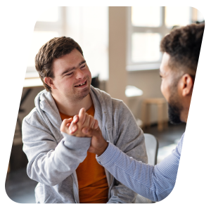 Two male colleagues smiling and shaking hands in an office.