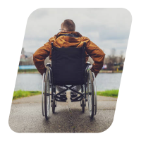 Person in a wheelchair looking out at a calm lake.
